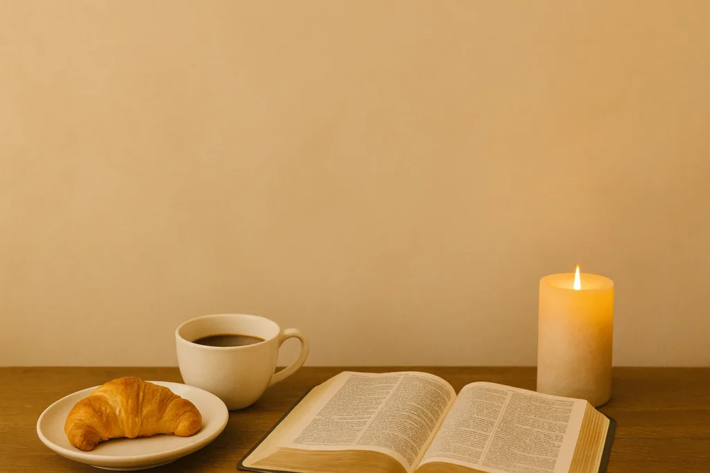 Cenário acolhedor com croissant e café sobre a mesa, ao lado de uma Bíblia aberta e uma vela acesa, sob luz suave da manhã em um ambiente sereno